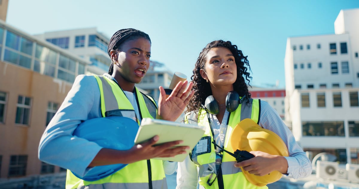 Safety auditor in high-vis vest reviewing plans with a team on a construction site